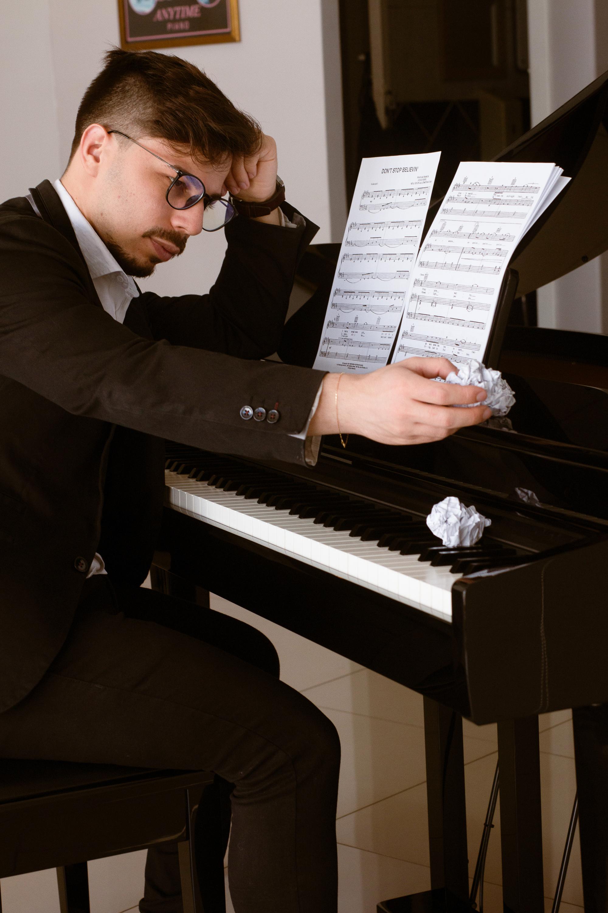 Gestor estressado com a mão na cabeça ao piano, segurando papel amassado, com partitura de 'Don't Stop Believin'' no piano